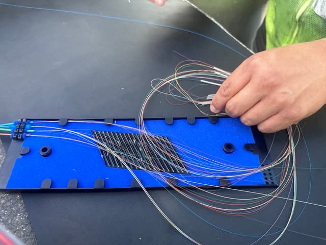 Technician feeding fiber into underground splice housing